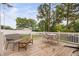 A serene back deck area with seating, a table, and views of the fenced backyard and trees at 5400 Kaplan Dr, Raleigh, NC 27606