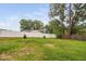 View of fenced backyard with green grass and trees from behind a white vinyl fence at 5400 Kaplan Dr, Raleigh, NC 27606
