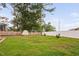 A well-maintained backyard with a mix of green grass, trees, and a fenced perimeter at 5400 Kaplan Dr, Raleigh, NC 27606