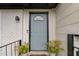 Charming light blue front door with a half-round window, flanked by potted plants and a white brick wall at 5400 Kaplan Dr, Raleigh, NC 27606