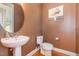 Half-bathroom with dark-painted walls, pedestal sink, and floral wall decor at 605 Bellefont Ct, Knightdale, NC 27545