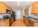 Bright kitchen with wood cabinets, stainless steel dishwasher, and black appliances at 605 Bellefont Ct, Knightdale, NC 27545