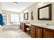 Bathroom featuring dual vanities, dark wood cabinets, decorative mirrors, and a soaking tub at 626 Toledo Ct, Rolesville, NC 27571