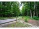 View of the long, gravel driveway leading to a secluded property surrounded by lush trees and a wooden fence at 698 Maple Springs Ln, Bear Creek, NC 27207