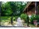 Brick path leading to covered porch, surrounded by lush landscaping and mature trees at 698 Maple Springs Ln, Bear Creek, NC 27207