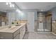 Bright bathroom with double sinks, vanity with granite counters, and tiled shower at 7 Faircroft Ct, Durham, NC 27703