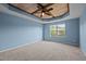 Spacious blue bedroom with unique tray ceiling and fan at 7 Faircroft Ct, Durham, NC 27703