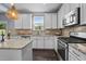 Well-lit kitchen with stainless appliances, white cabinets, granite counters, and a window view at 7 Faircroft Ct, Durham, NC 27703