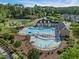 An aerial view shows a community pool, splash pad, playground, and tennis courts surrounded by mature trees at 7 Faircroft Ct, Durham, NC 27703