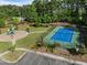 An aerial view shows a community tennis court and playground nestled among mature trees and green space at 7 Faircroft Ct, Durham, NC 27703