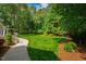 A serene backyard offers a manicured lawn, lush greenery, and a peaceful walking path at 7620 Rainwater Rd, Raleigh, NC 27615