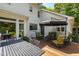 A charming white house boasts a wooden deck with an umbrella, dining set, and cozy seating area at 7620 Rainwater Rd, Raleigh, NC 27615