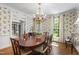 Bright dining room with wainscoting, floral wallpaper, large table, and chandelier at 7620 Rainwater Rd, Raleigh, NC 27615