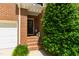 Charming brick home entrance featuring a small porch, front door, and manicured greenery at 7620 Rainwater Rd, Raleigh, NC 27615