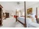 Large main bedroom with a four-poster bed, sitting area, ensuite access, and plush carpet at 7620 Rainwater Rd, Raleigh, NC 27615