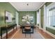 Elegant dining room with hardwood floors, green walls, modern lighting, and large windows with natural light at 815 Laurelwood Dr, Durham, NC 27705