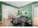 Open-concept dining room featuring hardwood floors, a large green wall and a modern black wood table at 815 Laurelwood Dr, Durham, NC 27705