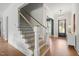 Bright entryway featuring wood floors, a staircase with black iron railings, and a modern chandelier at 815 Laurelwood Dr, Durham, NC 27705