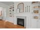 Close-up of a fireplace with white mantle, grey tile surround, built-in shelving and hardwood floors at 815 Laurelwood Dr, Durham, NC 27705