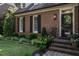 Close-up of a brick home's entrance, featuring a dark front door, black shutters, and manicured landscaping at 815 Marlowe Rd # 10, Raleigh, NC 27609