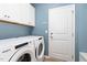 Laundry room with modern appliances, upper cabinets, and a convenient exterior door at 1025 Quindell Dr, Holly Springs, NC 27540