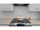 Modern kitchen featuring stainless steel gas cooktop, white subway tile backsplash, granite countertops, and white cabinetry at 10513 Cardington Ln, Raleigh, NC 27614