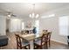 Dining area featuring modern chandelier, wood floors, with living and fireplace in background at 1125 Russet Ln, Apex, NC 27523
