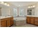 Bathroom with dual sinks, vanity, granite counters, and a garden tub with tile surround at 1148 Survada Ln, Morrisville, NC 27560