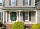 Close up of front door and porch with brick foundation and green shrubbery at 120 E Laurenbrook Ct, Cary, NC 27518