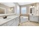 Bright bathroom with white vanities, tile flooring, mirrors, soaking tub and natural light at 129 Middlegreen Pl, Holly Springs, NC 27540
