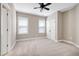 Neutral bedroom boasts a ceiling fan, carpet floors, and large windows at 129 Middlegreen Pl, Holly Springs, NC 27540
