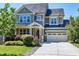 Charming two-story home with a manicured front yard and attached two-car garage on a sunny day at 129 Middlegreen Pl, Holly Springs, NC 27540