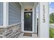 Stylish front door with wreath, stone accents, and house number enhancing curb appeal at 1313 Littlehills Dr, Apex, NC 27523