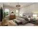 Well-lit main bedroom with hardwood floors, a tufted headboard, and a decorative chandelier at 135 Gary Rd, Carrboro, NC 27510