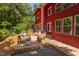 Exterior view of the red house featuring a wooden deck, a ramp, ample windows, and serene natural landscaping at 1409 Valley, Durham, NC 27707