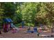 Community playground with colorful play structures, a slide, seesaws, and a picnic table under a canopy of trees at 1409 Valley, Durham, NC 27707