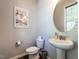 Cozy half-bathroom with a pedestal sink, round mirror, and stylish decor at 157 E Wilson St, Clayton, NC 27520