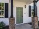 Close-up of a charming home entrance featuring an olive-green front door with brick pillars at 157 E Wilson St, Clayton, NC 27520