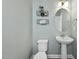 Charming powder room with a pedestal sink, oval mirror, and wire baskets for storage at 1604 Upper Park Rd, Wake Forest, NC 27587
