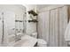 Neutral bathroom featuring a combined shower and bathtub with wood look shelves and a cream colored curtain at 1604 Upper Park Rd, Wake Forest, NC 27587