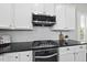 Close-up of kitchen with white cabinetry, subway tile backsplash, stainless steel appliances, and dark countertop at 1604 Upper Park Rd, Wake Forest, NC 27587