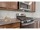 Close-up of a modern kitchen with stainless steel appliances, granite countertops, and ample storage space in wooden cabinets at 1745 Ripley Woods St, Wake Forest, NC 27587
