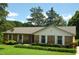 Charming brick ranch-style home with manicured lawn and mature trees under a blue sky at 1815 Chandellay Dr, Durham, NC 27705