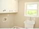 Bright laundry room with utility sink, white cabinets, and window for natural light at 1815 Chandellay Dr, Durham, NC 27705