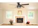 Cozy living room with fireplace, mantel mirror, updated ceiling fan, and natural light from dual windows at 1815 Chandellay Dr, Durham, NC 27705