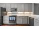 Modern kitchen with stainless steel appliances, gray cabinets, and mosaic tile backsplash at 1815 Crystal Downs Lane, Raleigh, NC 27604