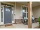 Charming front porch with rocking chairs, a gray front door, and a stacked stone accent wall at 184 Elgin Ct, Burlington, NC 27215