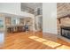 Open-concept living room with stone fireplace and hardwood floors adjacent to kitchen and staircase at 20002 Fountain, Chapel Hill, NC 27517