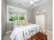 Bright bedroom featuring a patterned bedspread, white ceiling fan, and natural light from a large window at 2112 Dunn Rd, Raleigh, NC 27614