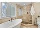 Bright bathroom with a glass-enclosed shower, soaking tub, and neutral tiling, offering a peaceful retreat at 217 Dalmeny Dr, Cary, NC 27513